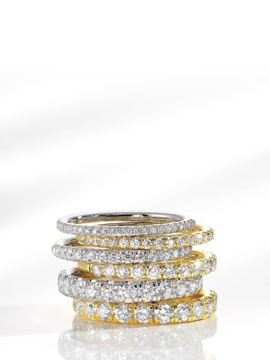 Stack of gold and silver rings with diamond accents on a white background