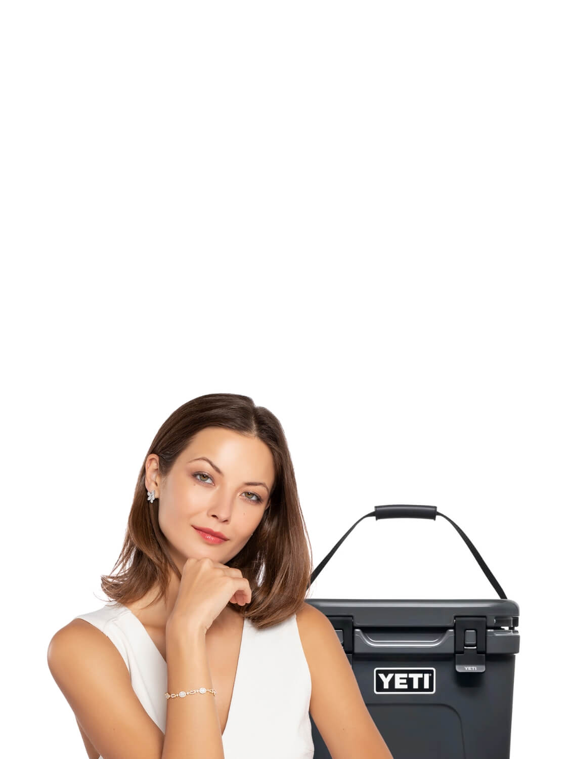 Woman with diamond bracelet and earringsstanding next to a YETI cooler on a white background