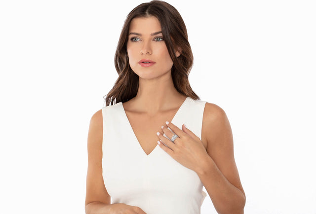 Woman wearing a white sleeveless top and diamond jewelry on a white background