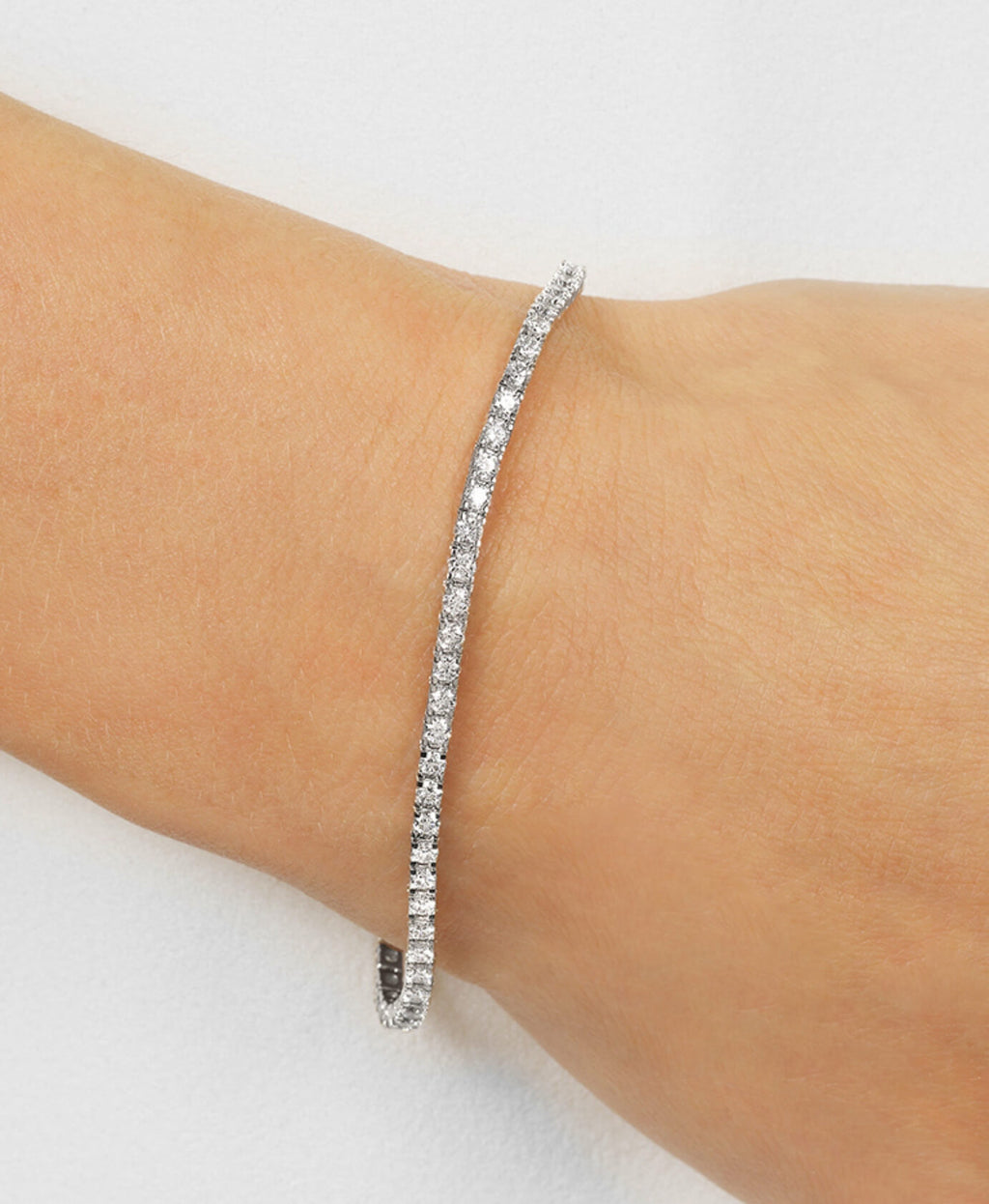 Silver diamond bracelet on a wrist against a white background