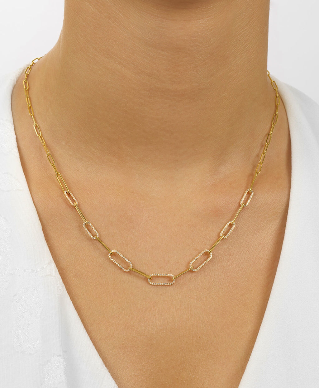 Gold chain necklace on a person wearing a white top