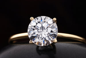 Gold ring with a large diamond on a black background
