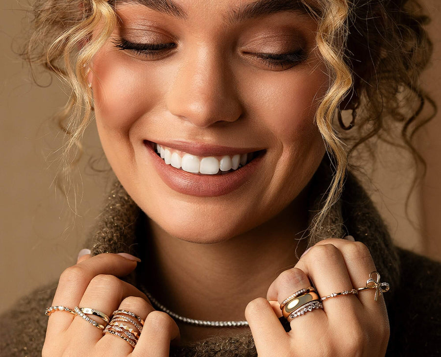 Woman wearing multiple rings on her fingers with a neutral background