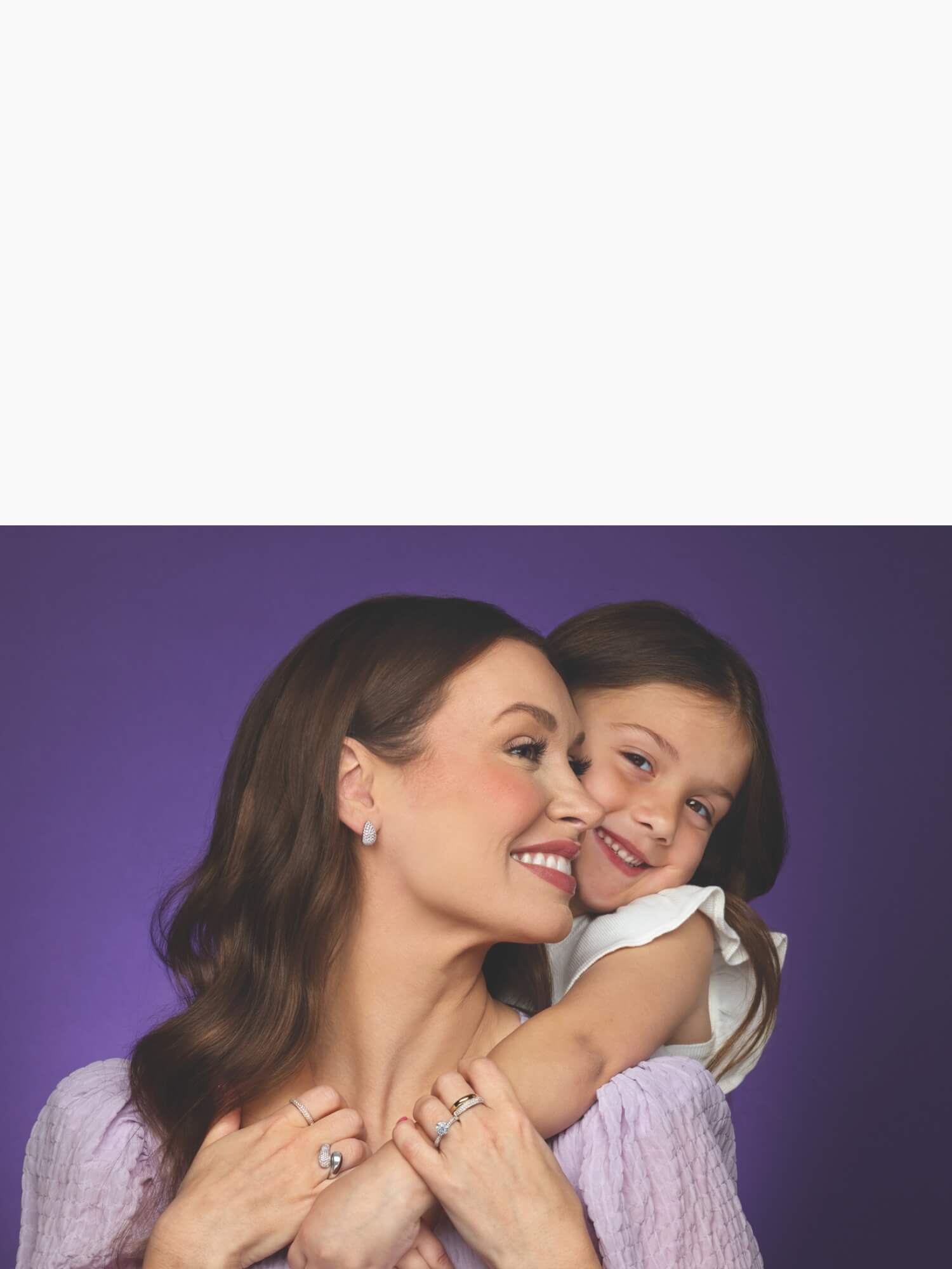 Woman wearing jewelry and a child embracing with a silver watch displayed on a white background