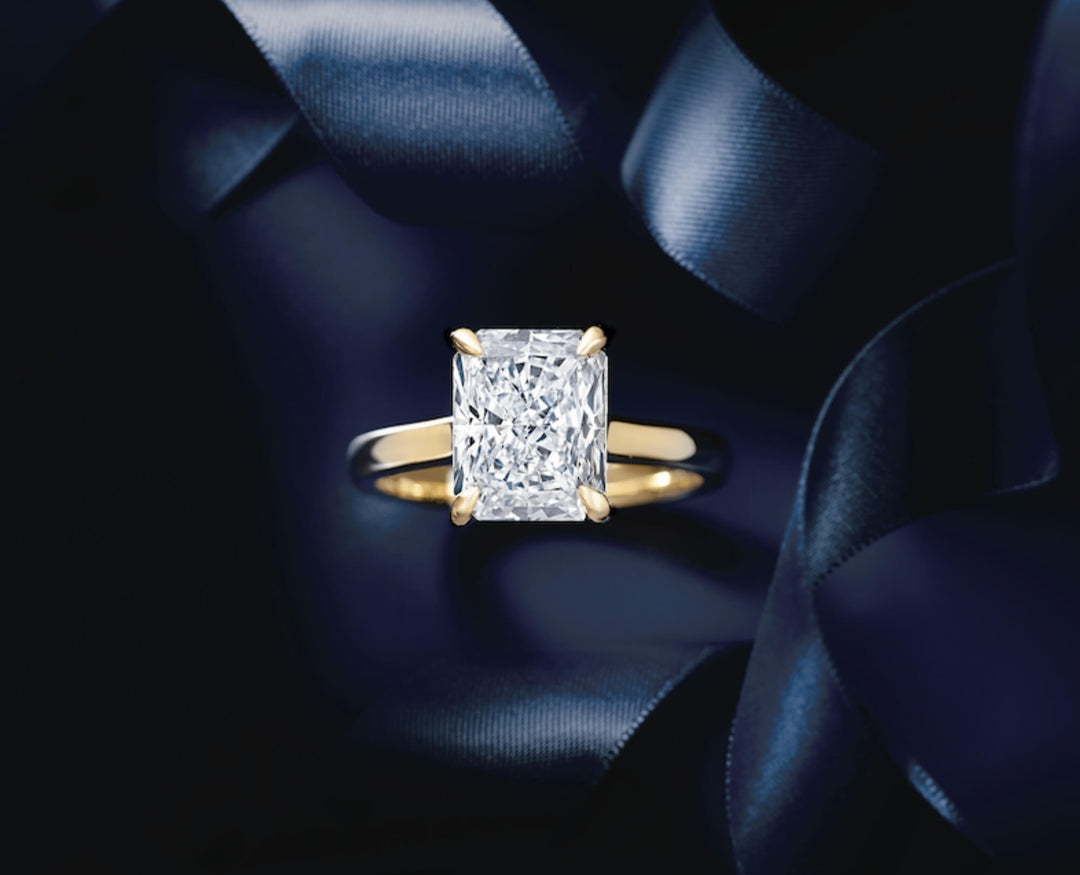 Gold ring with a diamond on a dark blue satin background