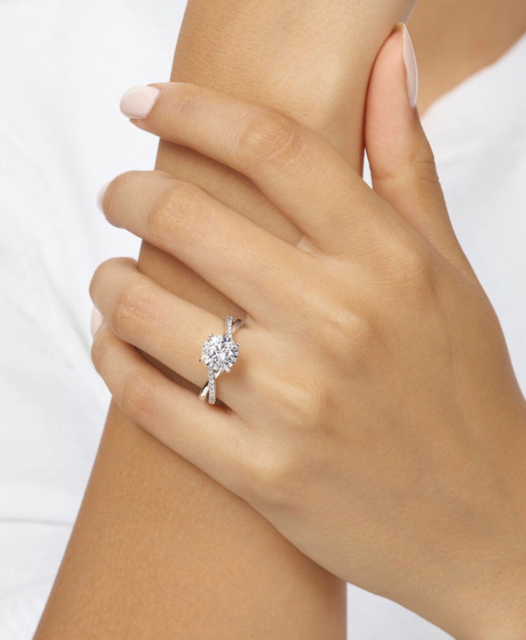 Close-up of a hand wearing a diamond ring on a white background