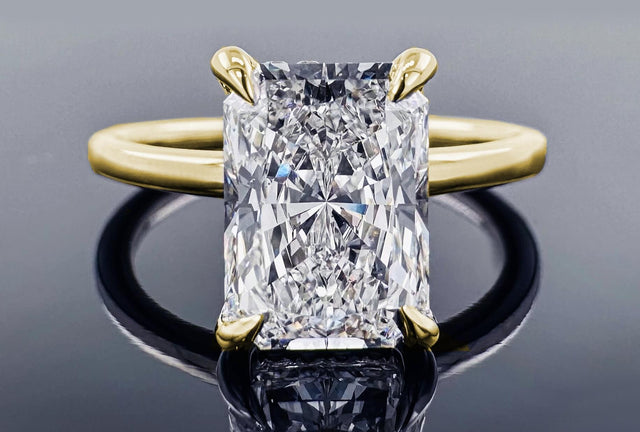 Gold ring with a large diamond on a reflective surface