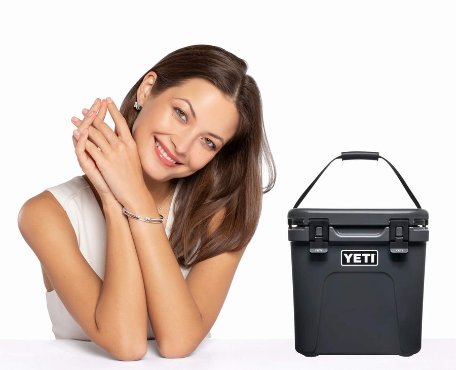 Woman with diamond bracelet posing next to a YETI cooler on a white background