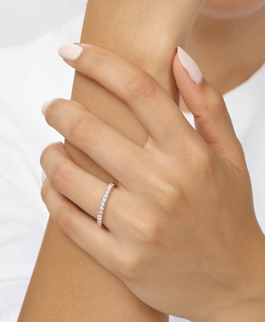 Close-up of a hand wearing a diamond ring on a white background
